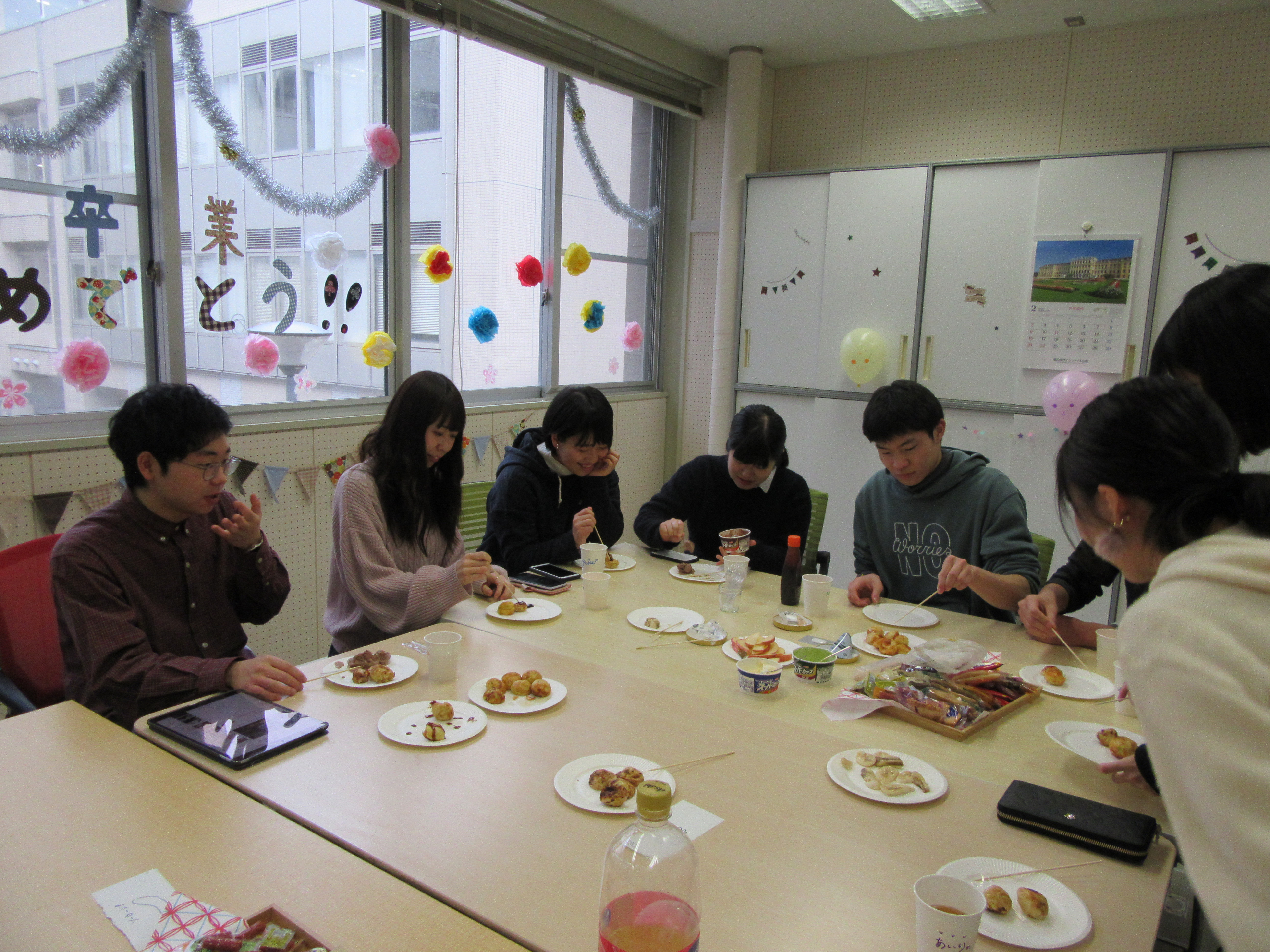 机を数名の学生が囲みたこ焼きを食べている