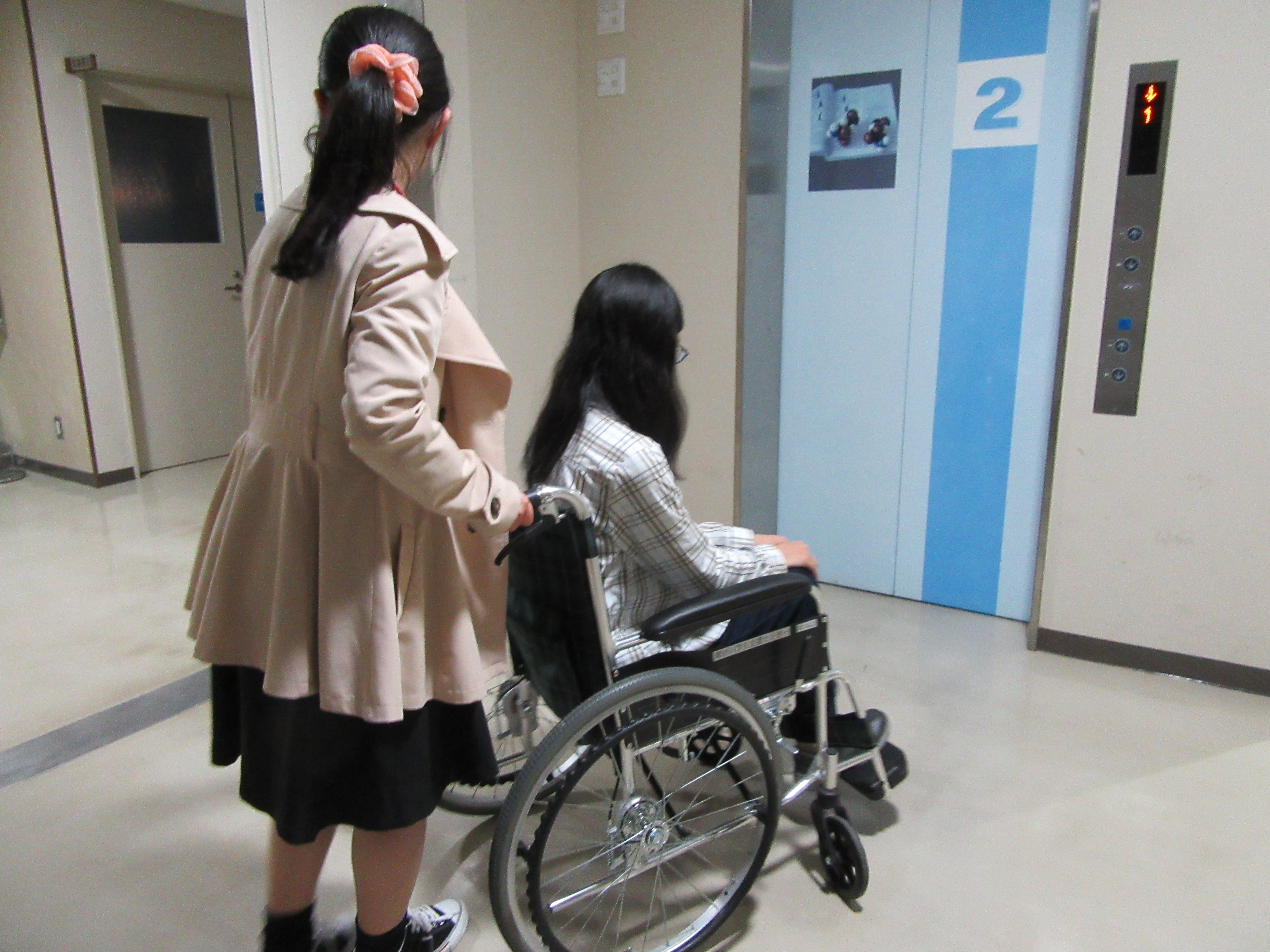 １人の受講生が車椅子に乗り、もう１人が車椅子を押す体験をしている