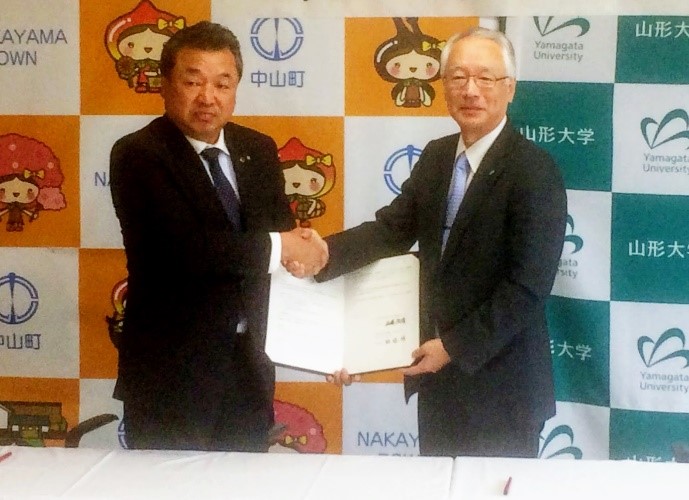 握手を交わす佐藤町長（左）と飯塚学部長の画像