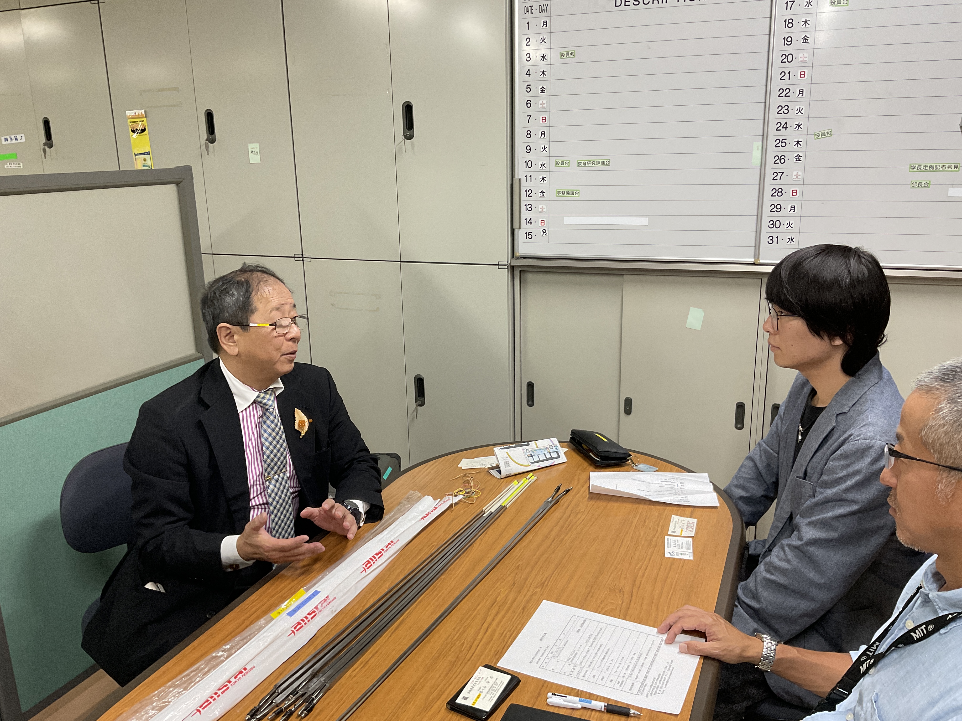 佐々木様（左）から寄贈品（フェンシング剣）の説明を受ける赤石さん（右）の画像