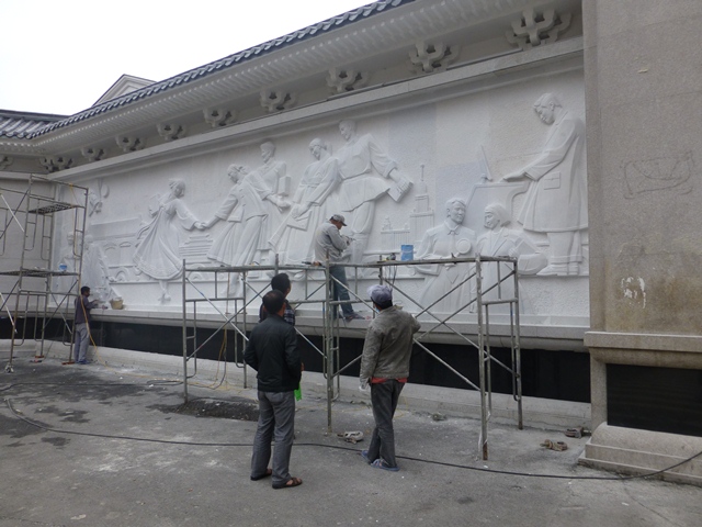 延辺大学正門の壁面に彫刻を施す職人の画像