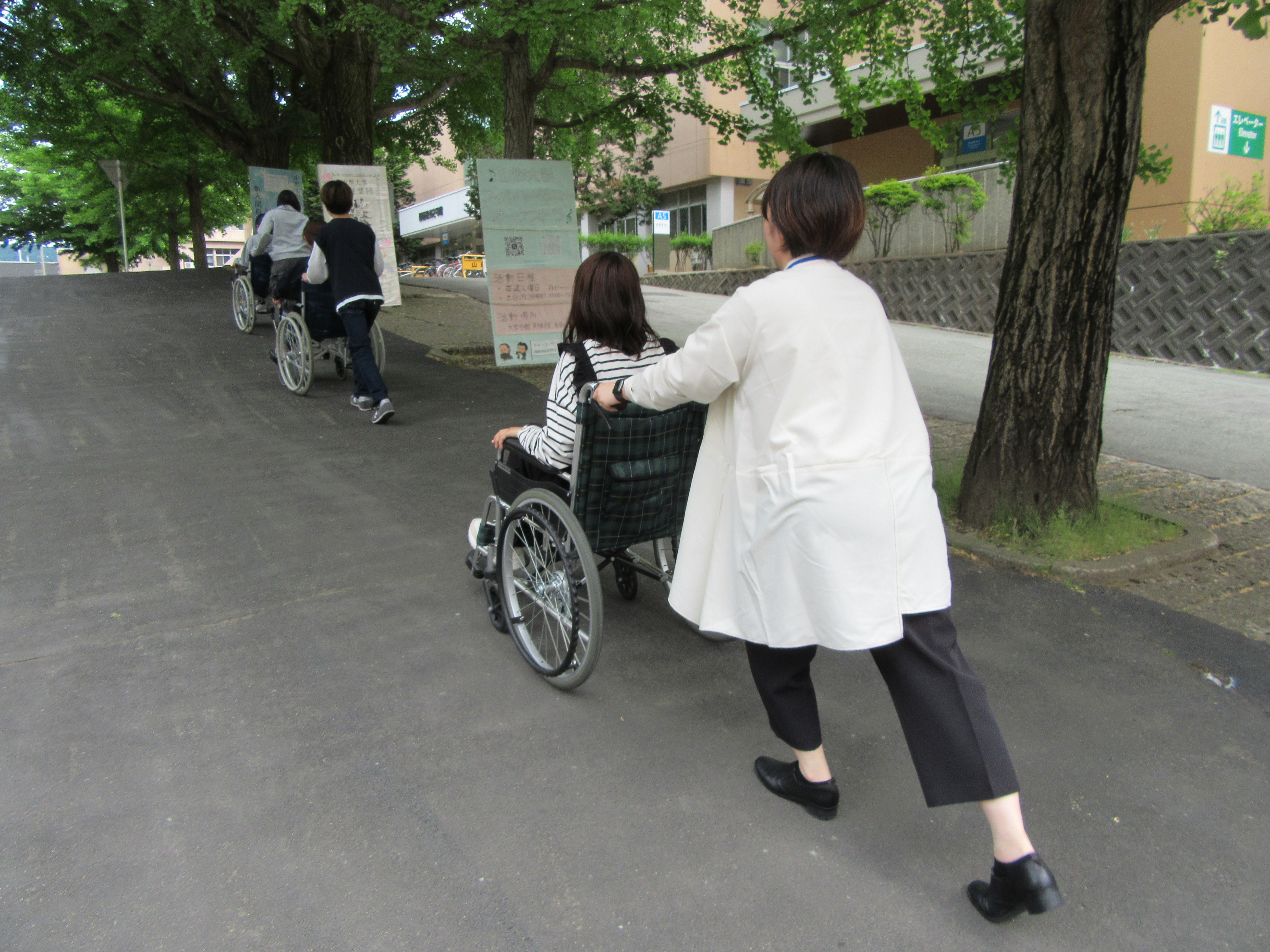 ２人ずつの３組が車いすを使用し、坂をのぼっている