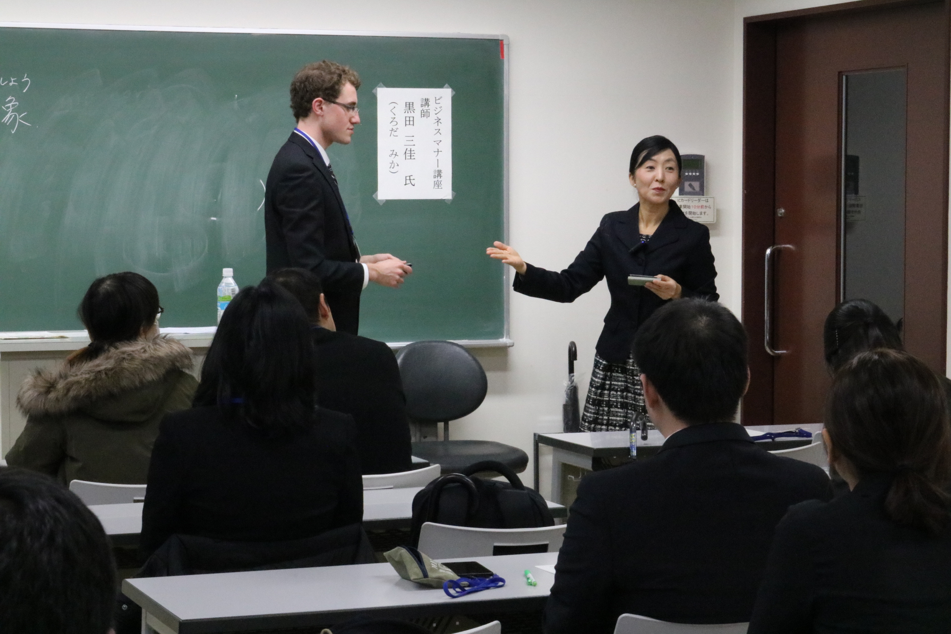 名刺の渡し方の指導を受ける学生の画像
