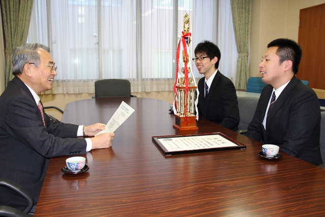 小山学長に報告する高橋さん（中）と東海林さん（右）の画像