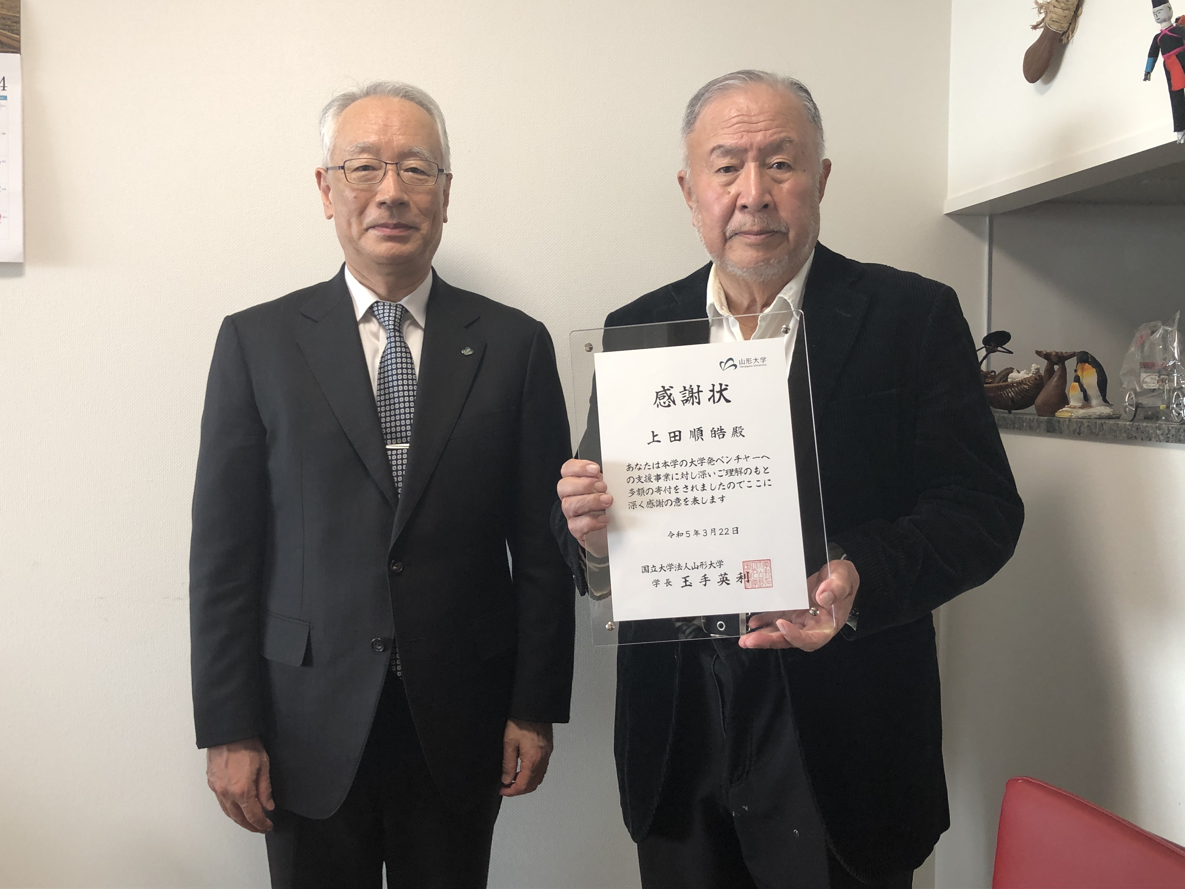 上田様（右）に感謝状を贈呈する飯塚理事・副学長の画像