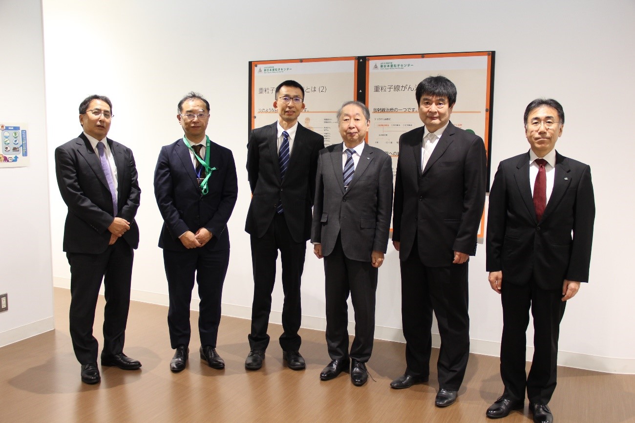 写真左から　根本理事、岩井センター長、俵課長、玉手学長、上野医学部長、土谷病院長の画像