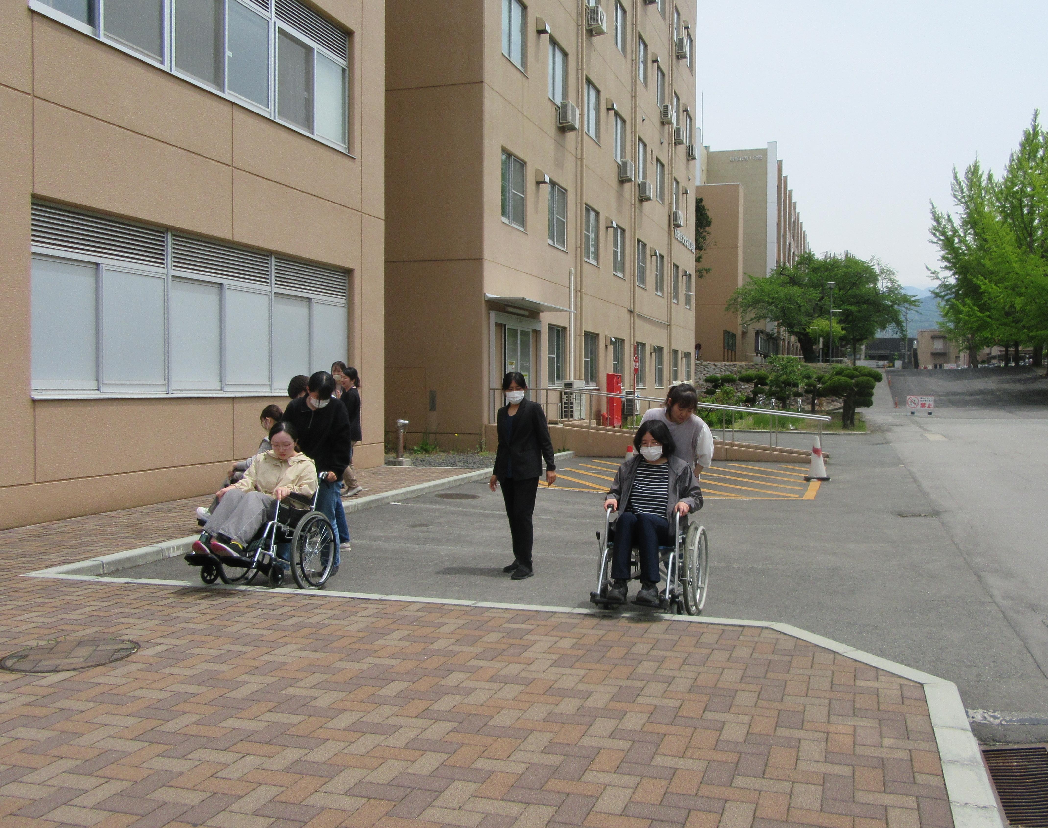 外の段差を使用して、車いすであがったり、おりたり、練習している様子の写真。