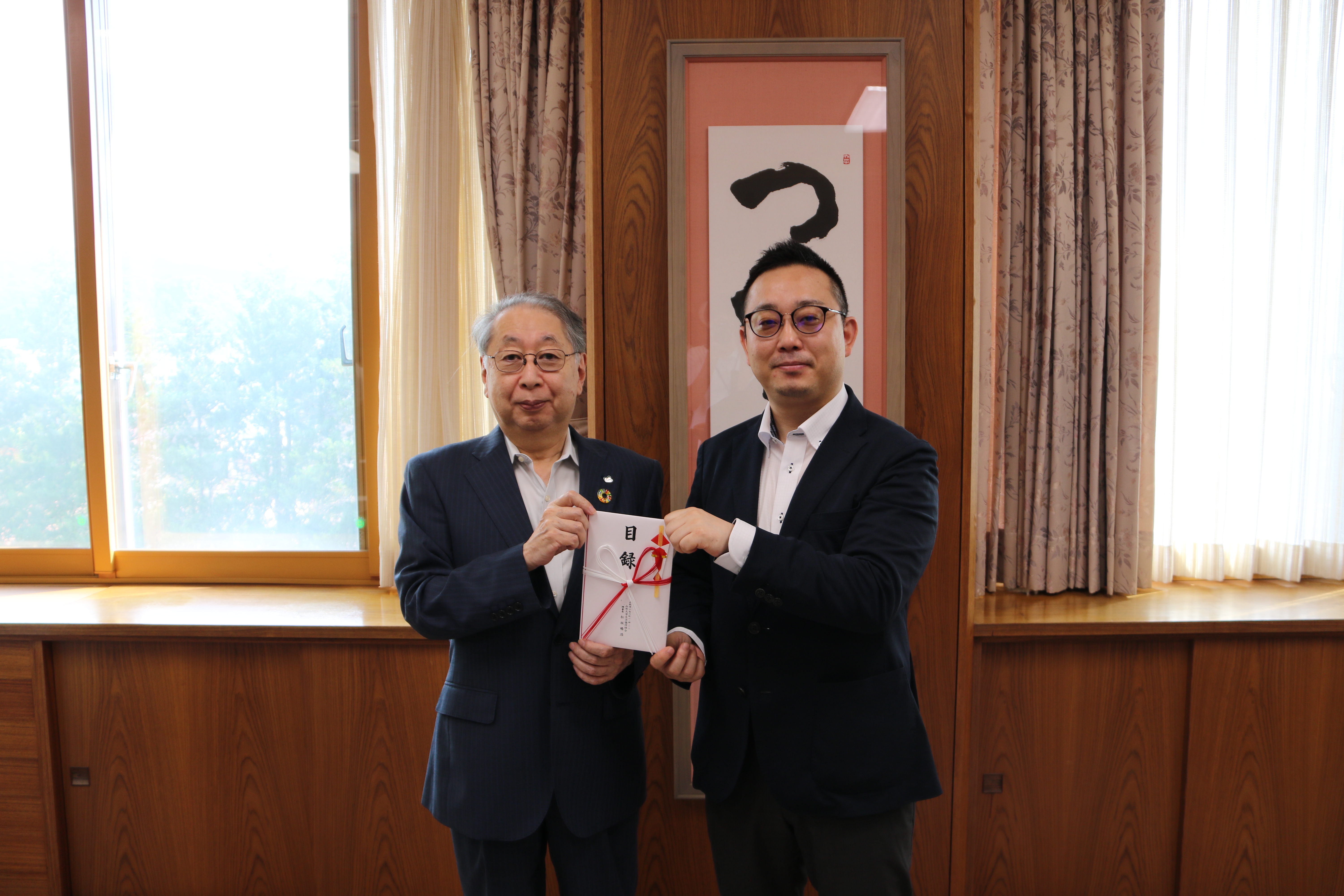 松坂暢浩理事長（右）から目録を贈呈される玉手学長の画像
