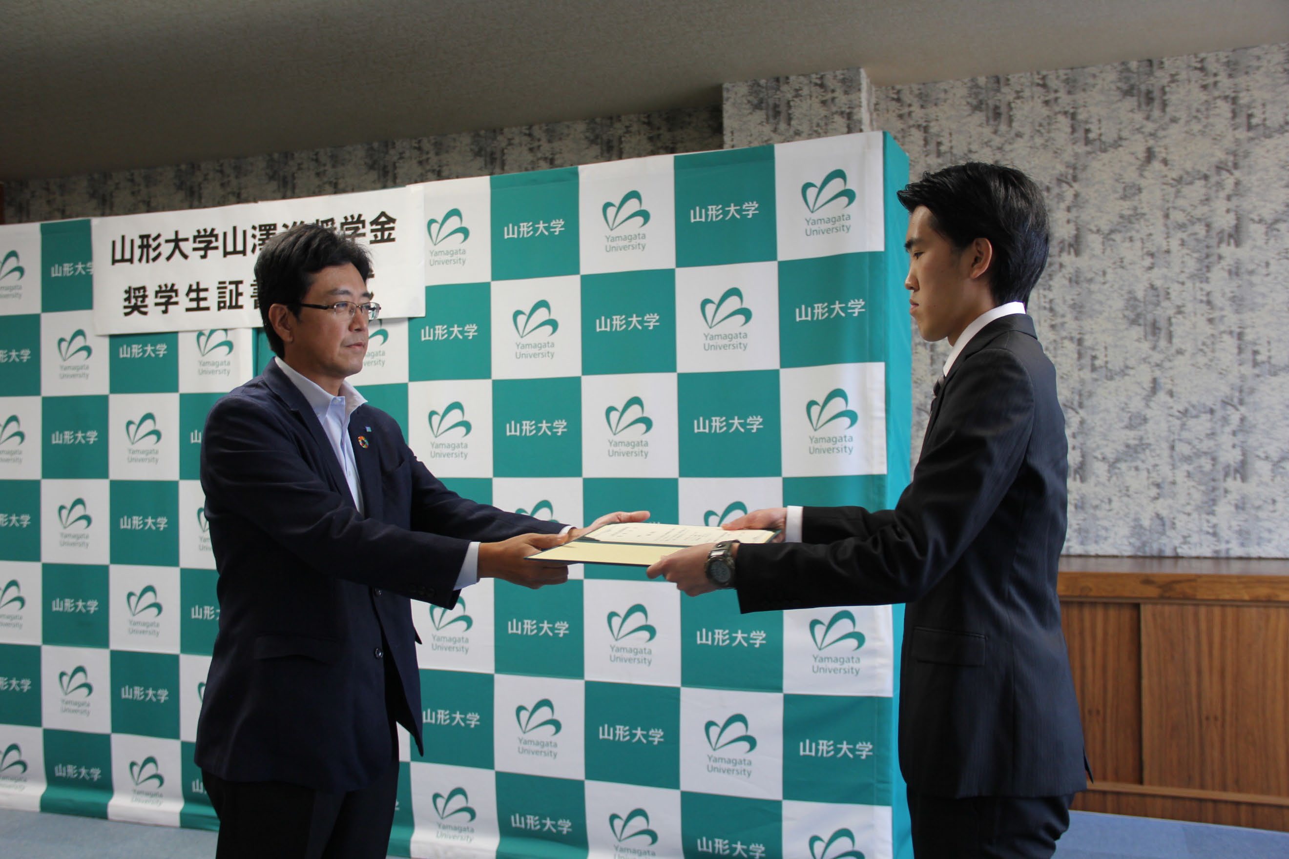奨学生証書授与（左：山澤代表理事、右：工学部・西坂さん）の画像
