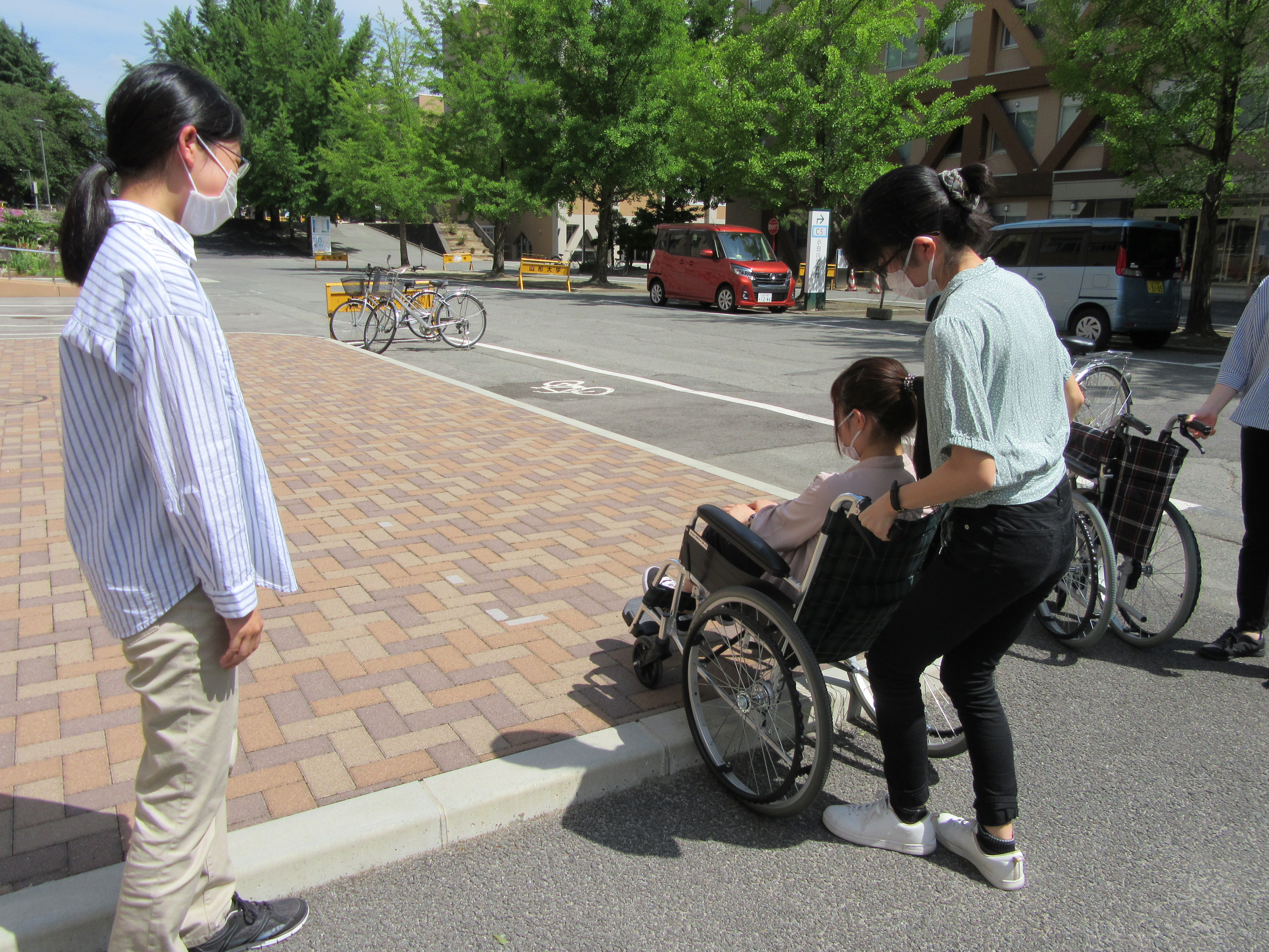 １人の受講生が車椅子に乗り、もう１人は車椅子を押して段差昇降の練習をしている